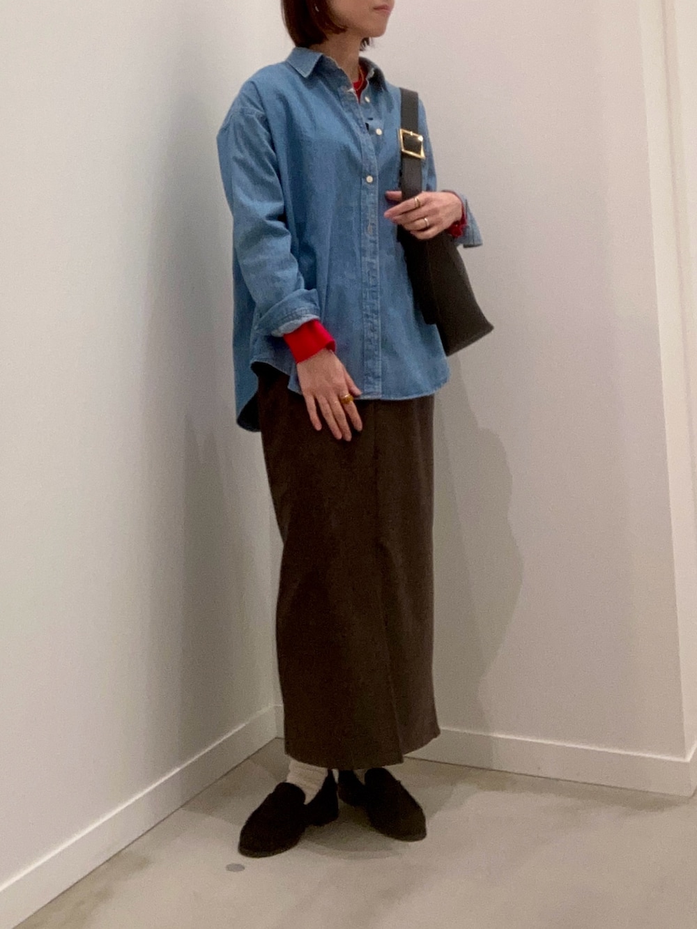 レッド系のニット/セーター、ブルー系のシャツ/ブラウス、ブラウン系のスカートを着用したレディースの冬コーディネートの3枚目の写真