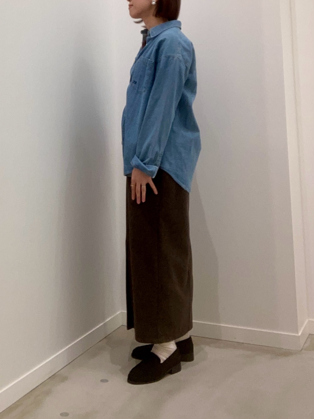 レッド系のニット/セーター、ブルー系のシャツ/ブラウス、ブラウン系のスカートを着用したレディースの冬コーディネートの6枚目の写真