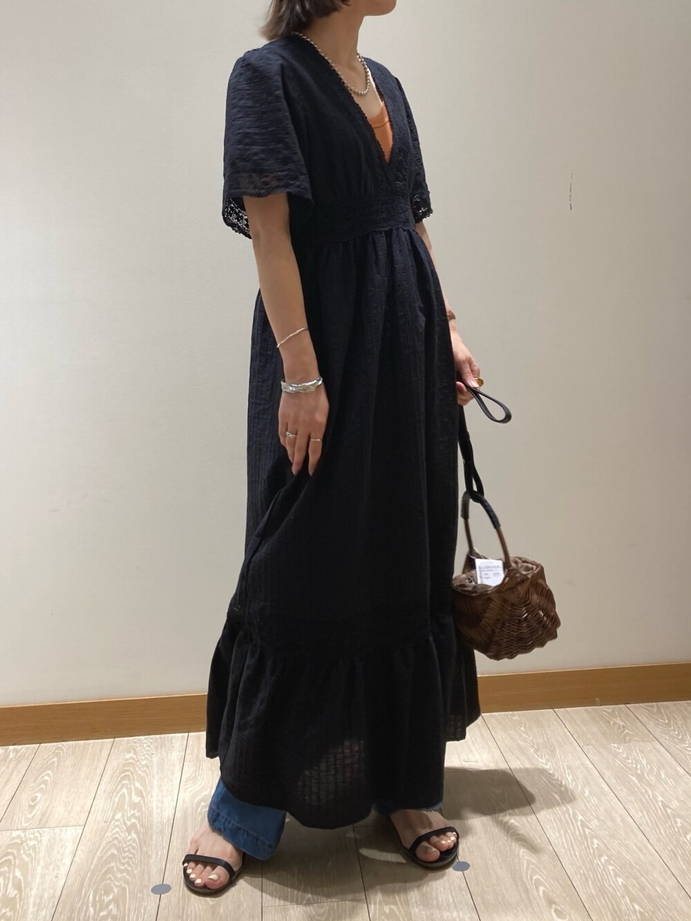 ブルー系のデニムパンツ、ブラック系のサンダル、ブラック系のワンピースを着用したレディースの夏コーディネートの3枚目の写真