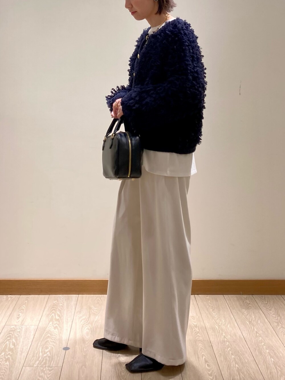 ブルー系のカーディガン/ボレロ、ブラック系のハンドバッグ、ホワイト系のTシャツ/カットソーを着用したレディースの冬コーディネートの6枚目の写真