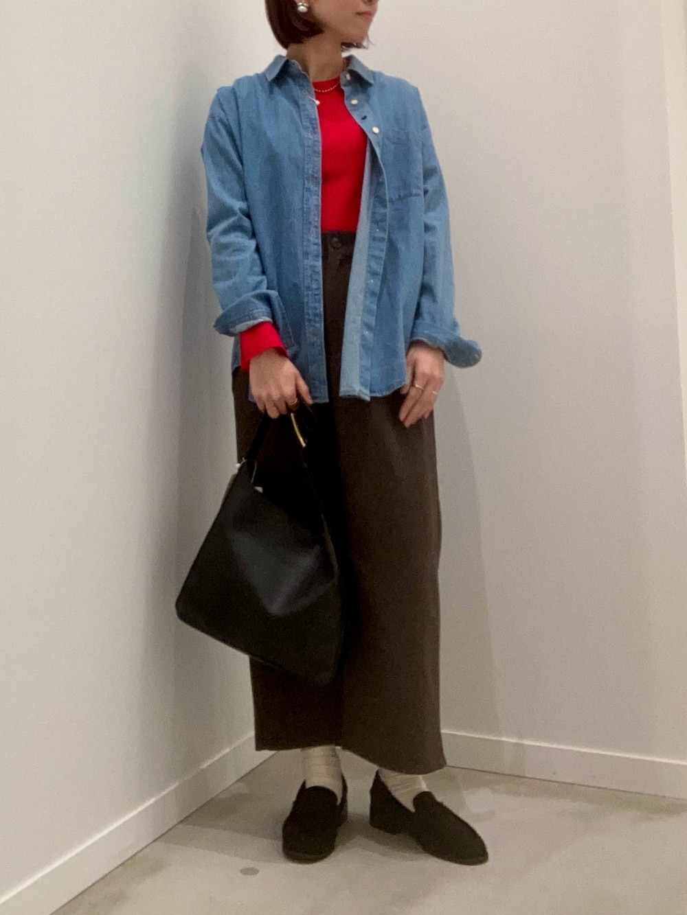 レッド系のニット/セーター、ブルー系のシャツ/ブラウス、ブラウン系のスカートを着用したレディースの冬コーディネートの2枚目の写真