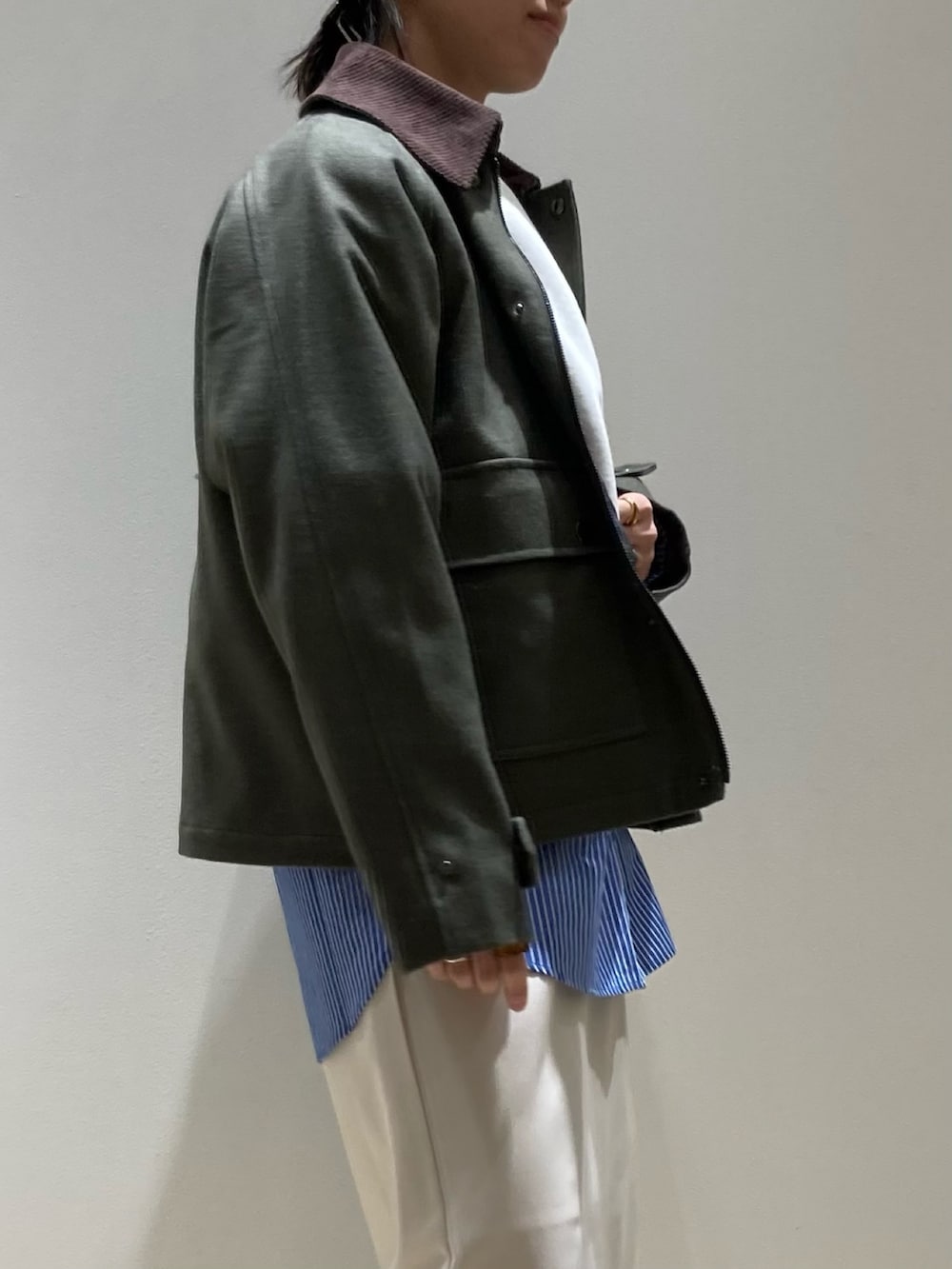 グリーン系のテーラードジャケット、グレー系のスウェット、ホワイト系のスカートを着用したレディースの冬コーディネートの3枚目の写真