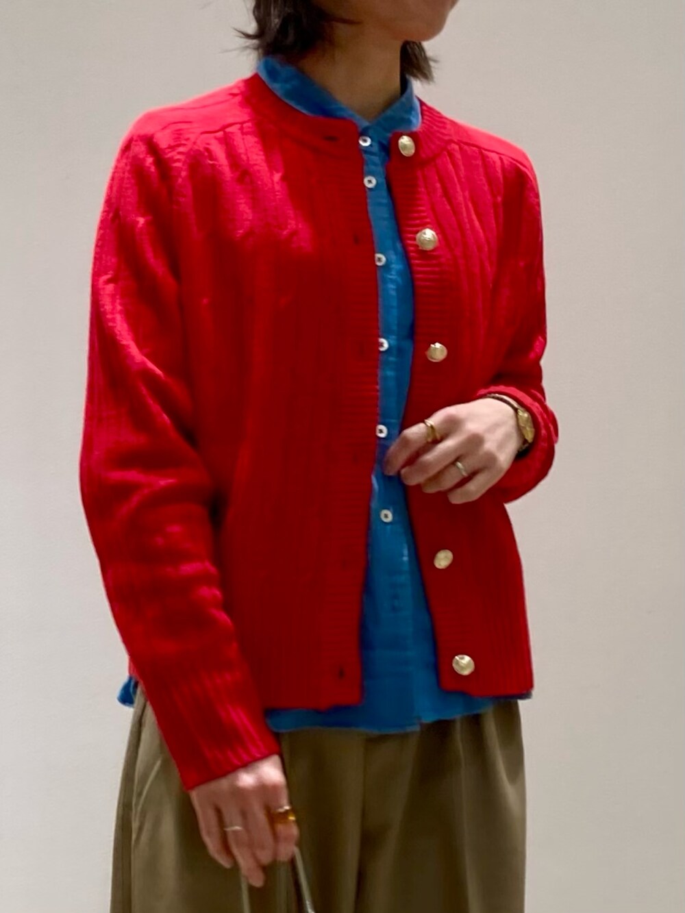 レッド系のカーディガン/ボレロ、ブラック系のブーツ、ベージュ系のスラックスを着用したレディースの冬コーディネートの6枚目の写真