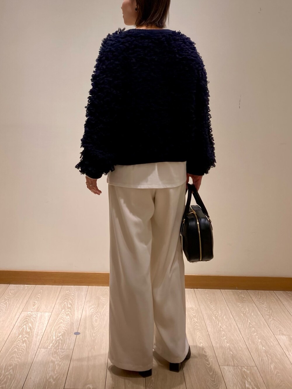 ブルー系のカーディガン/ボレロ、ブラック系のハンドバッグ、ホワイト系のTシャツ/カットソーを着用したレディースの冬コーディネートの5枚目の写真