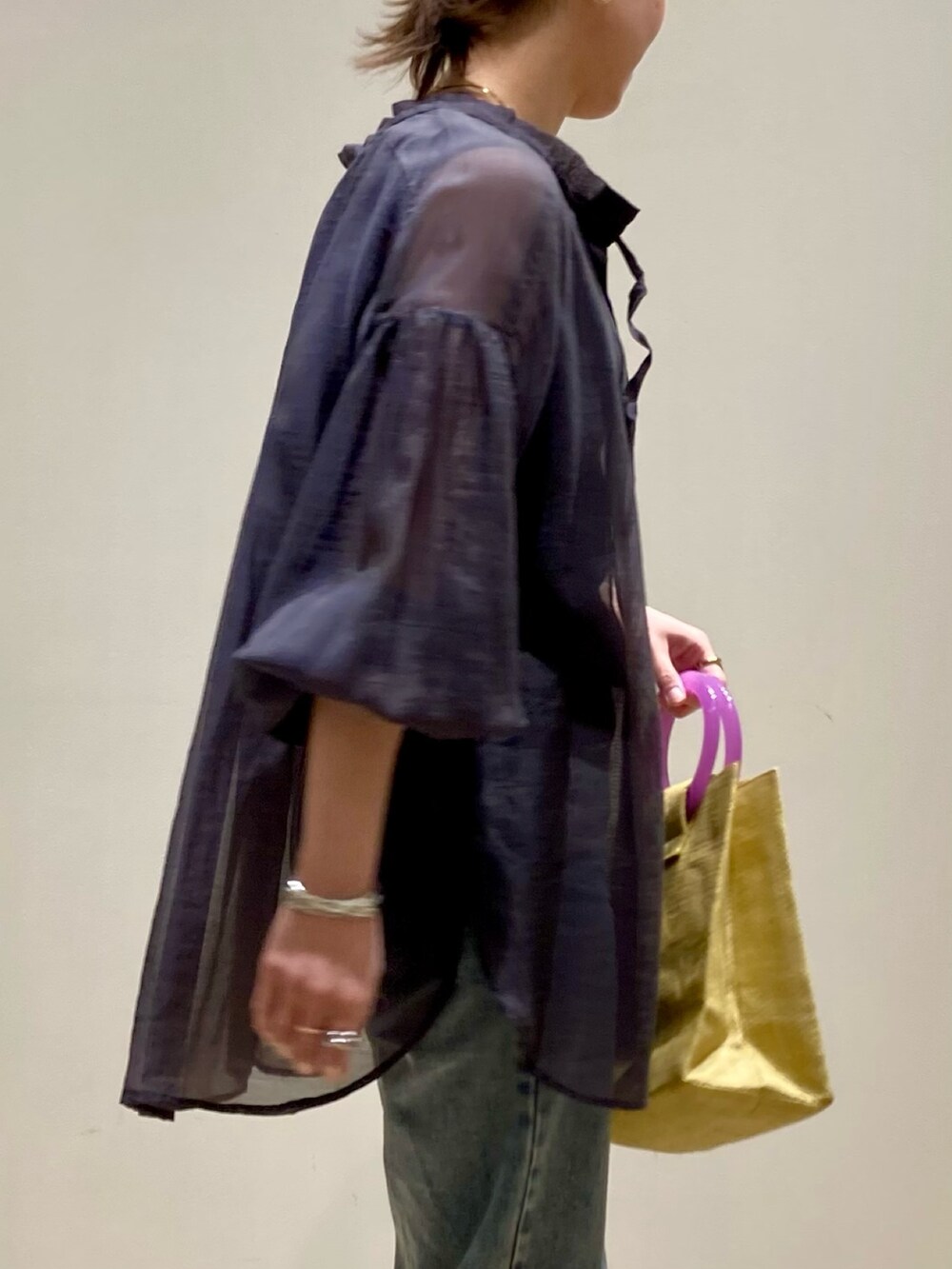 イエロー系のかごバッグ、ブルー系のデニムパンツ、ブラック系のパンプスを着用したレディースの春コーディネートの8枚目の写真