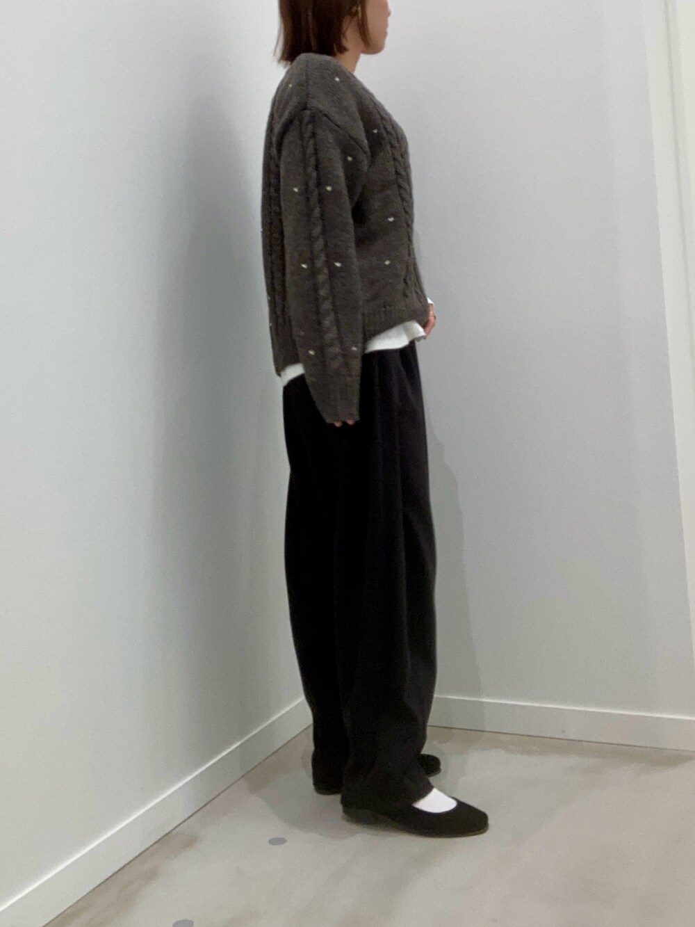 グレー系のニット/セーター、ホワイト系のTシャツ/カットソー、ブラック系のその他パンツを着用したレディースの秋コーディネートの4枚目の写真