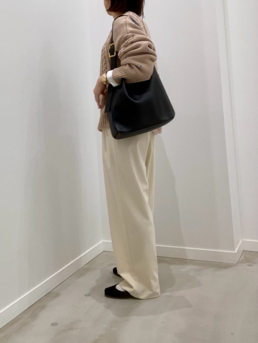 ベージュ系のニット/セーター、ホワイト系のTシャツ/カットソー、ブラック系のショルダーバッグを着用したレディースの秋コーディネートの5枚目の写真