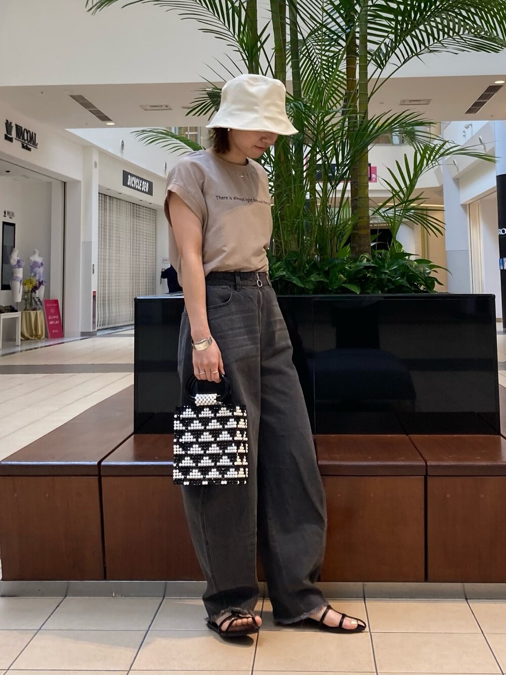 ブラック系のデニムパンツ、ブラック系のサンダル、ブラック系のトートバッグを着用したレディースの春コーディネートの2枚目の写真