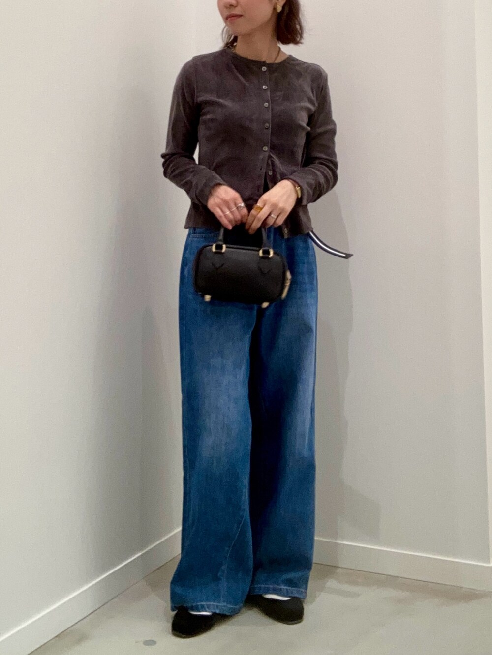 グレー系のカーディガン/ボレロ、ブルー系のデニムパンツ、ブラック系のショルダーバッグを着用したレディースの秋コーディネートの9枚目の写真