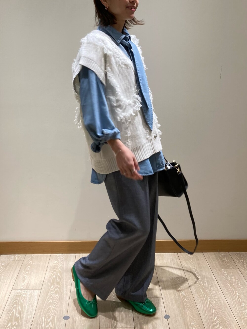 ブラック系のトートバッグ、ブルー系のスラックス、グリーン系のバレエシューズを着用したレディースの冬コーディネートの3枚目の写真