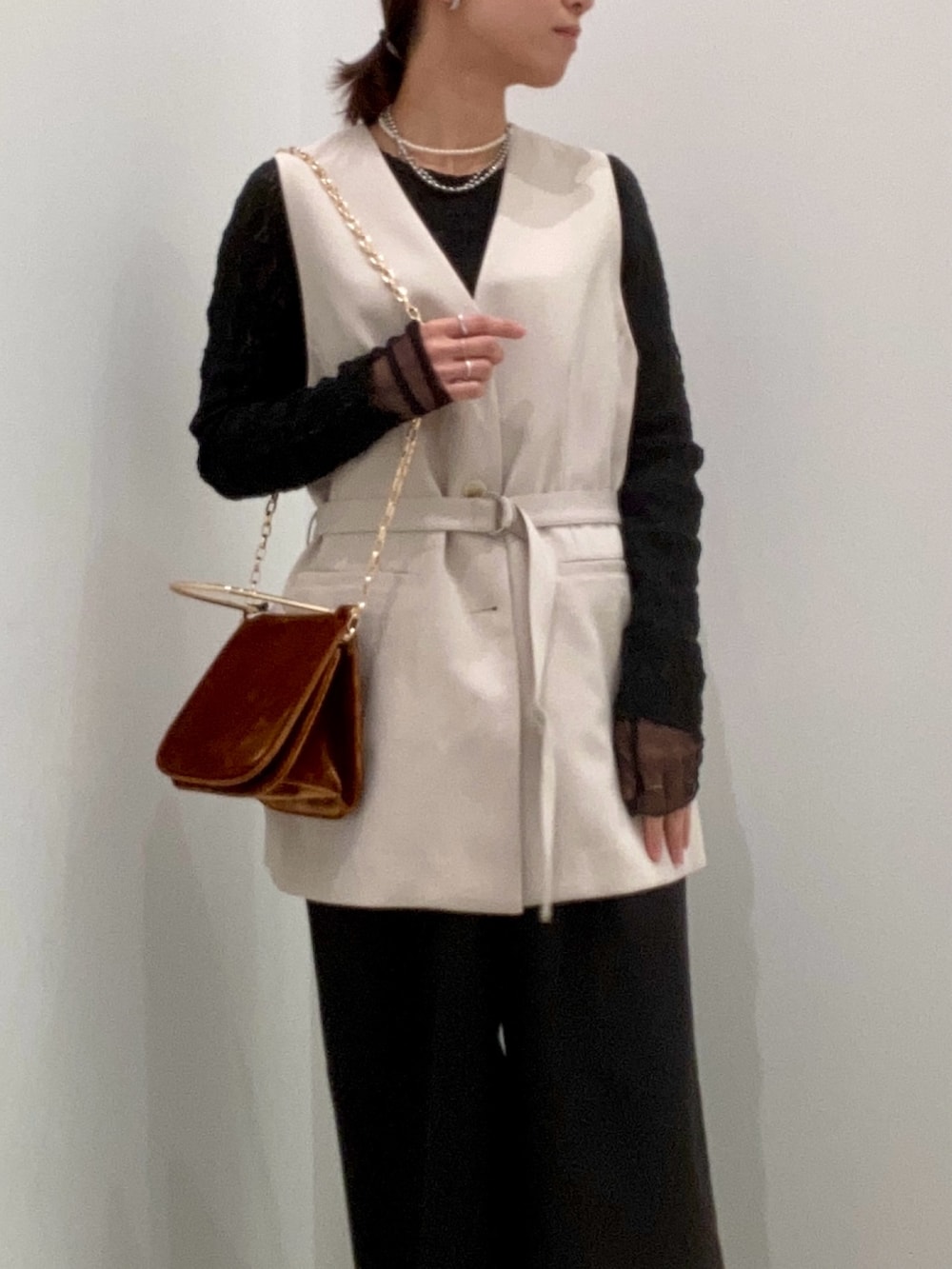 ベージュ系のベスト、ブラック系のTシャツ/カットソー、ブラウン系のショルダーバッグを着用したレディースの冬コーディネートの9枚目の写真