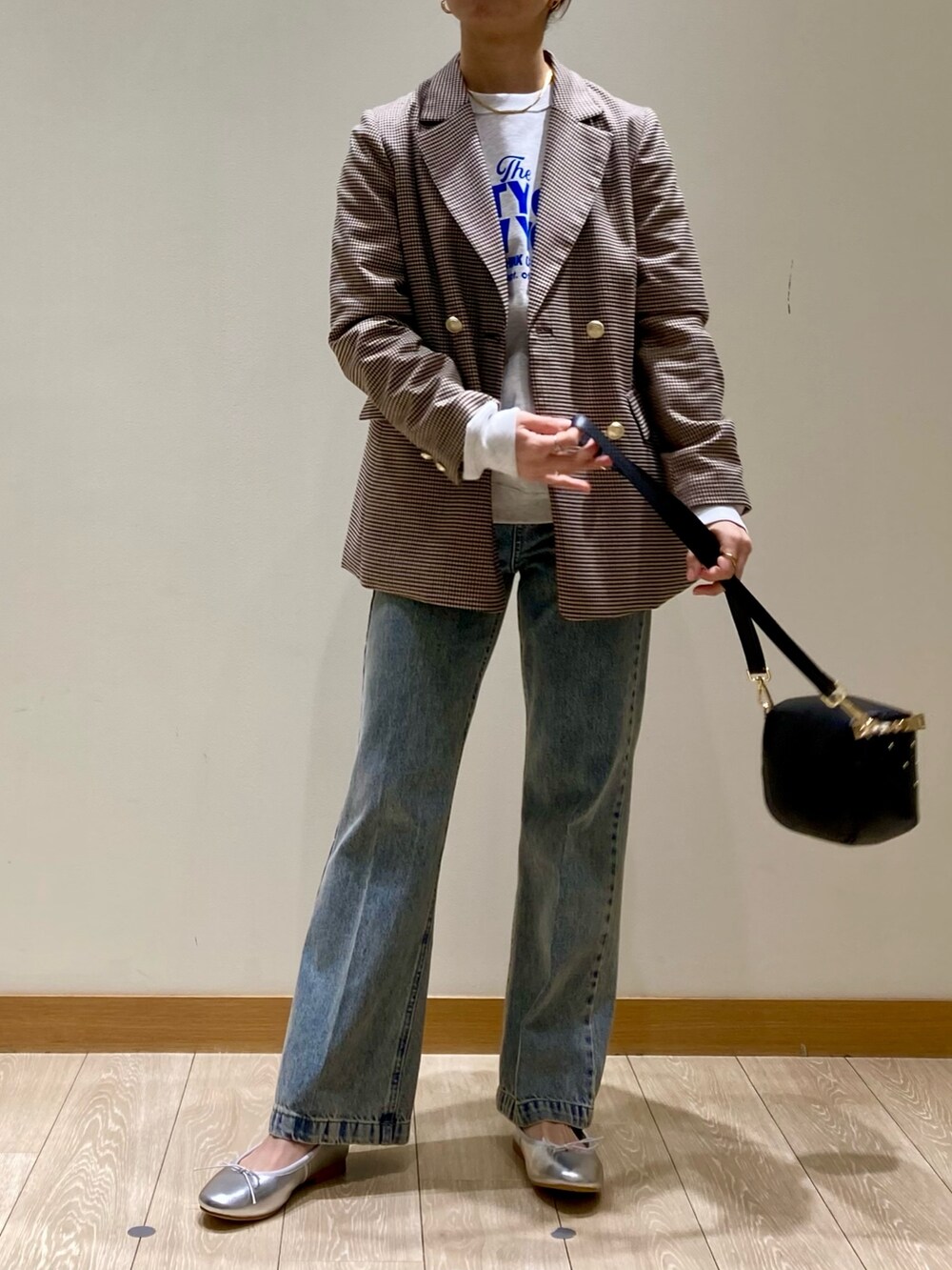 ブラック系のショルダーバッグ、ブルー系のデニムパンツ、シルバー系のバレエシューズを着用したレディースの冬コーディネートの2枚目の写真