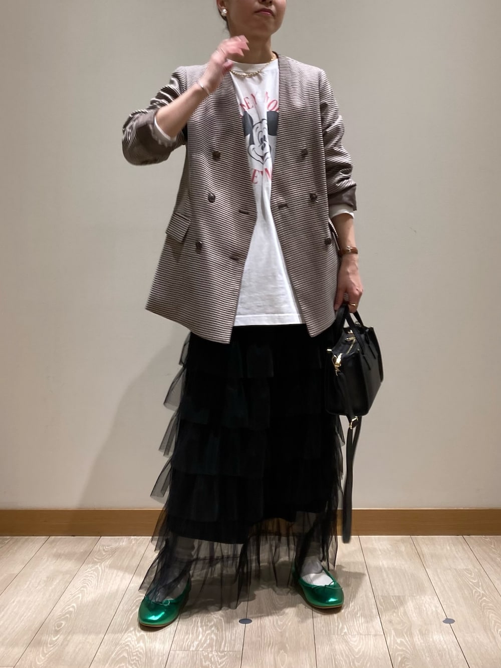 ブラック系のトートバッグ、ブラック系のスカート、グリーン系のバレエシューズを着用したレディースの春コーディネートの2枚目の写真