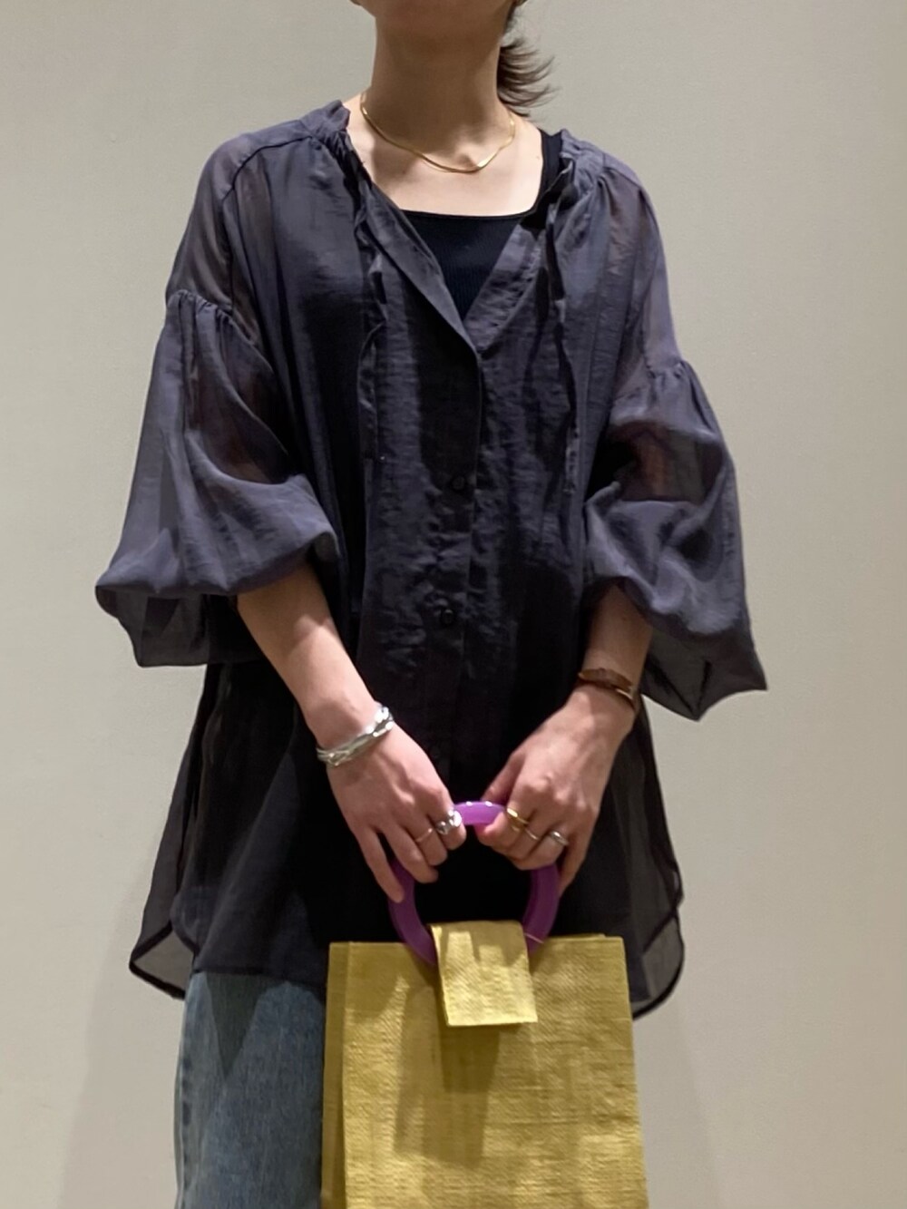 イエロー系のかごバッグ、ブルー系のデニムパンツ、ブラック系のパンプスを着用したレディースの春コーディネートの9枚目の写真