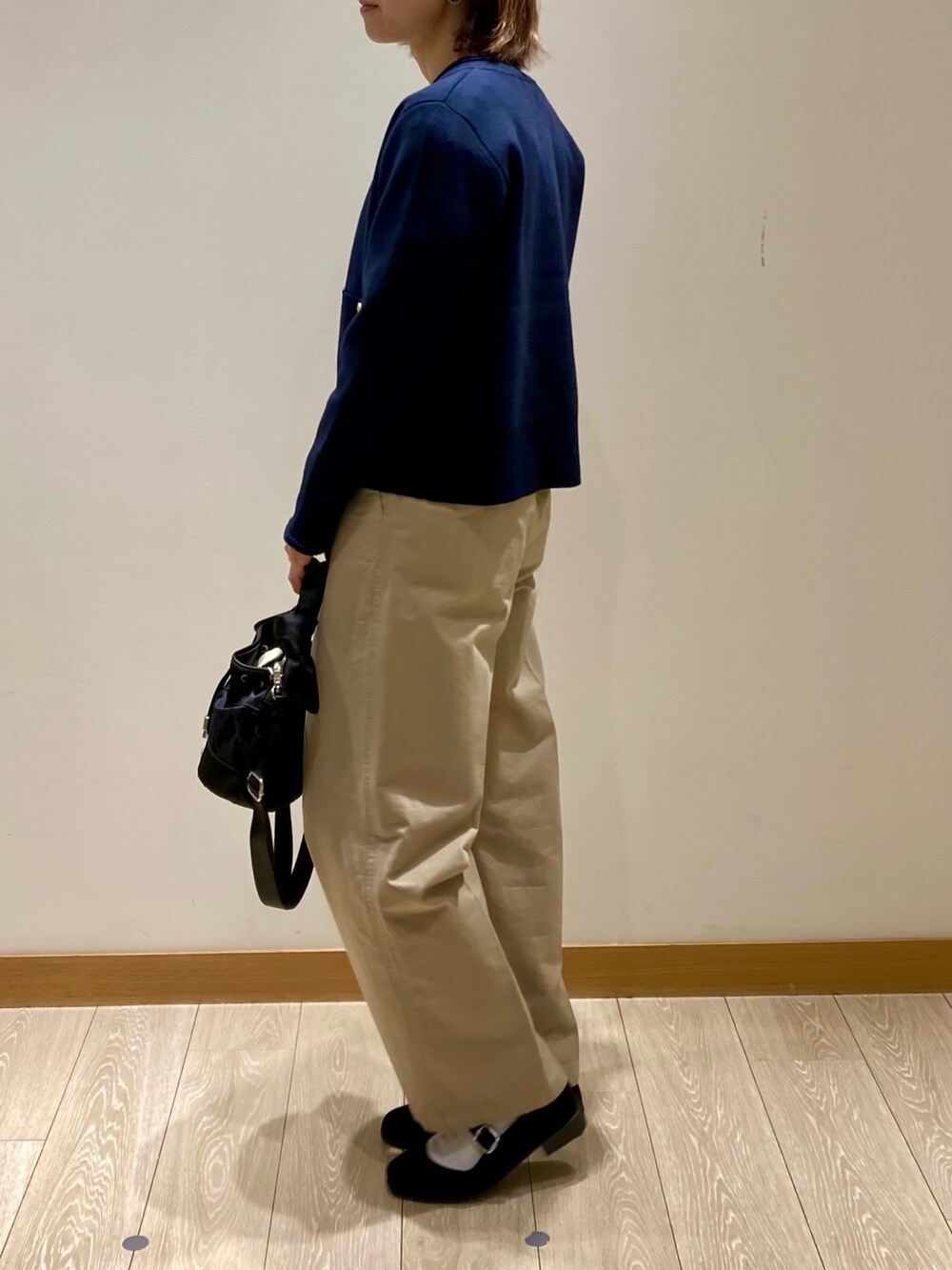 ブラック系のショルダーバッグ、ブルー系のカーディガン/ボレロ、ホワイト系のTシャツ/カットソーを着用したレディースの秋コーディネートの6枚目の写真