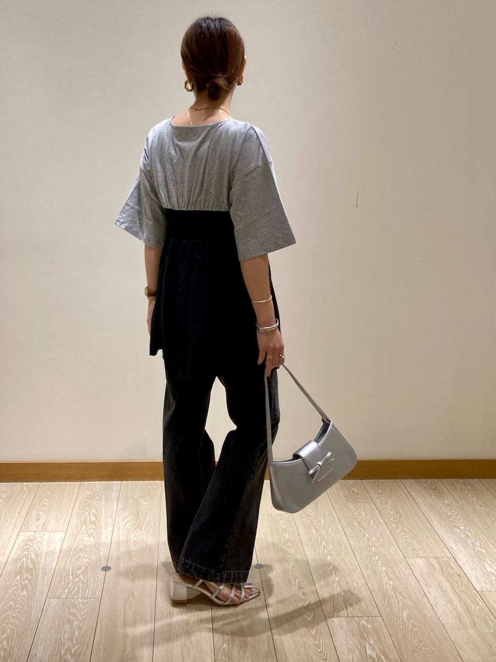 シルバー系のハンドバッグ、グレー系のTシャツ/カットソー、シルバー系のサンダルを着用したレディースの夏コーディネートの4枚目の写真