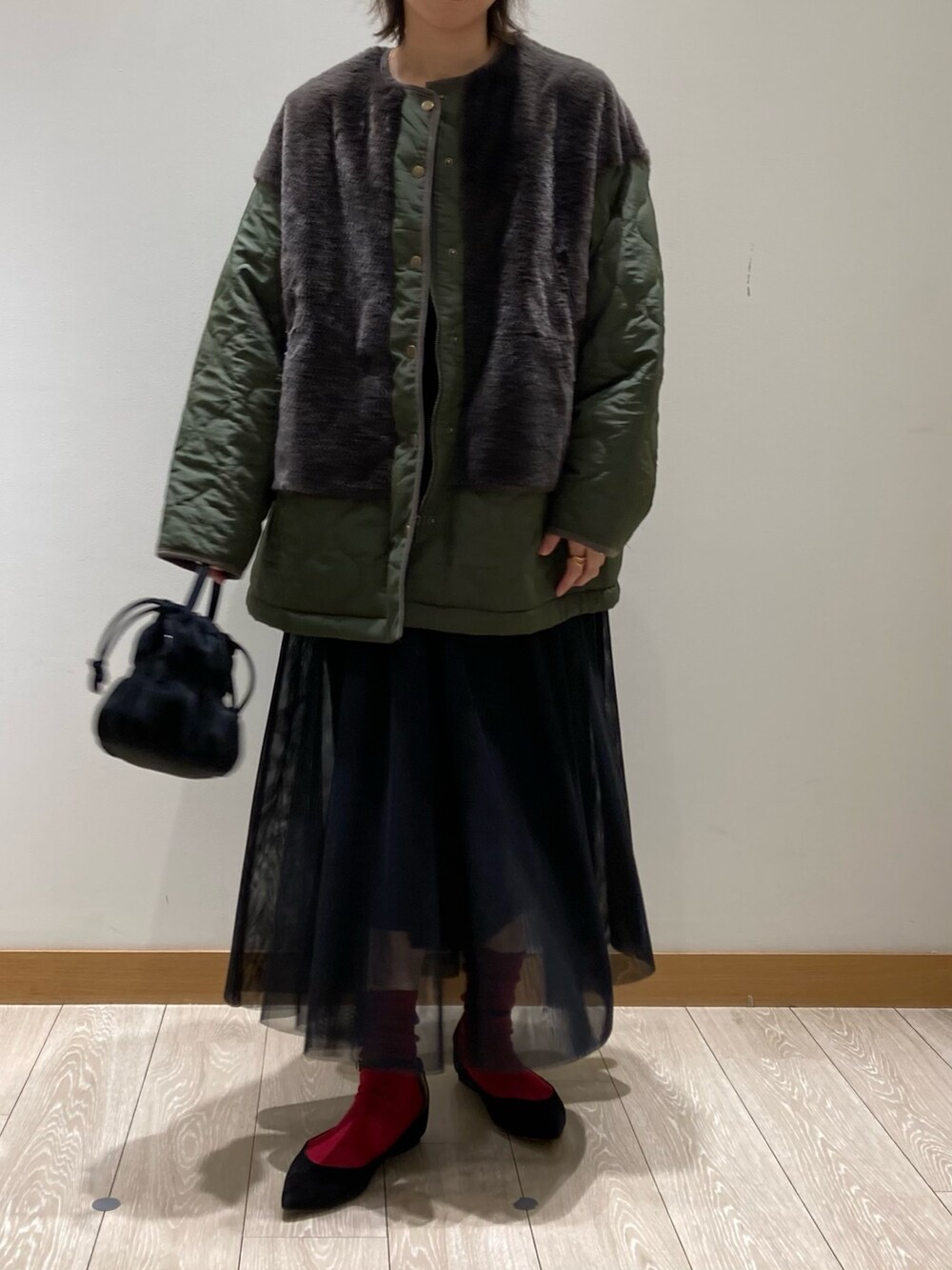 ブラック系のショルダーバッグ、ブラック系のワンピース、グリーン系のブルゾンを着用したレディースの冬コーディネートの2枚目の写真