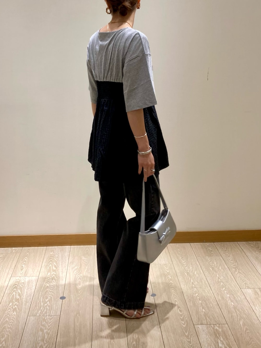 シルバー系のハンドバッグ、グレー系のTシャツ/カットソー、シルバー系のサンダルを着用したレディースの夏コーディネートの3枚目の写真