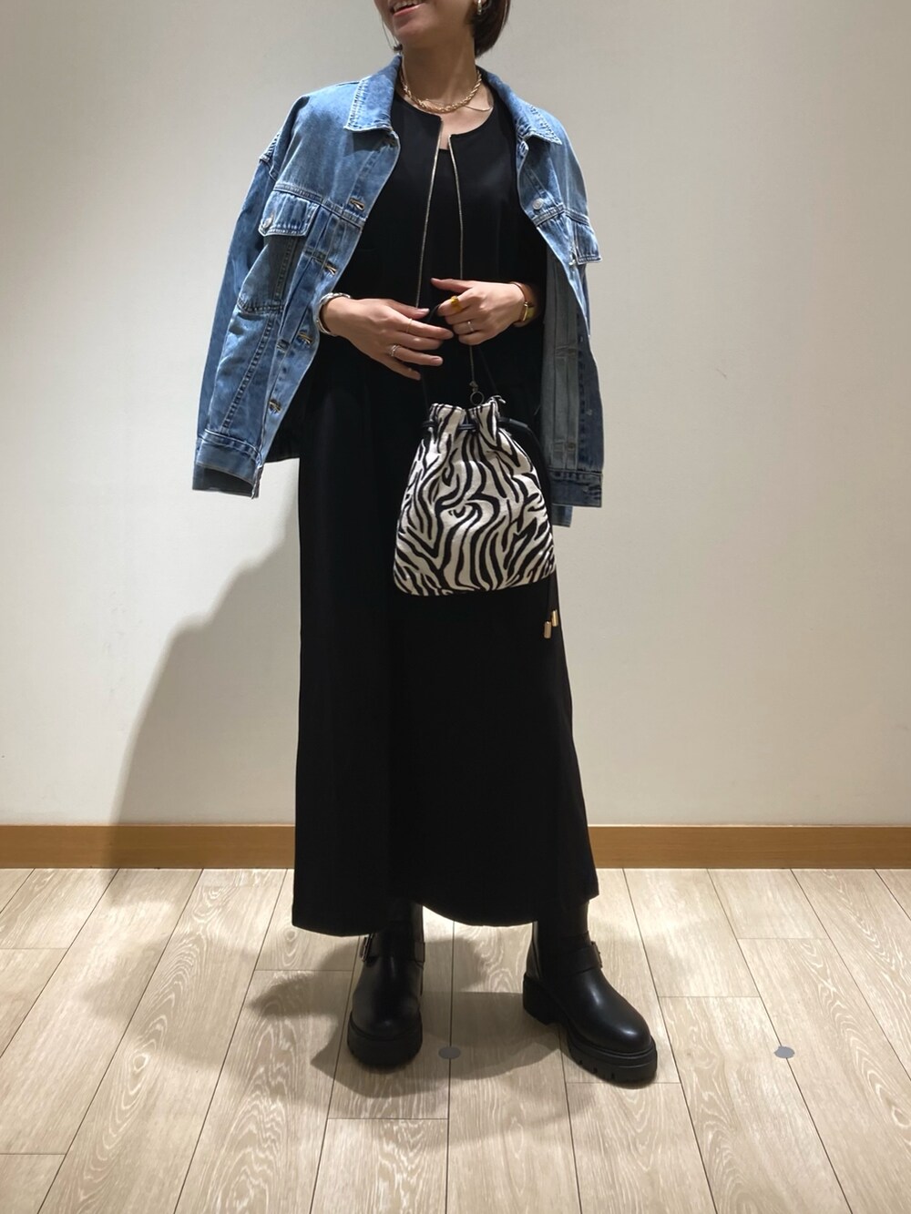 ブラック系のジャンパースカート、ブラック系のショルダーバッグ、ブラック系のブーツを着用したレディースの夏コーディネートの2枚目の写真