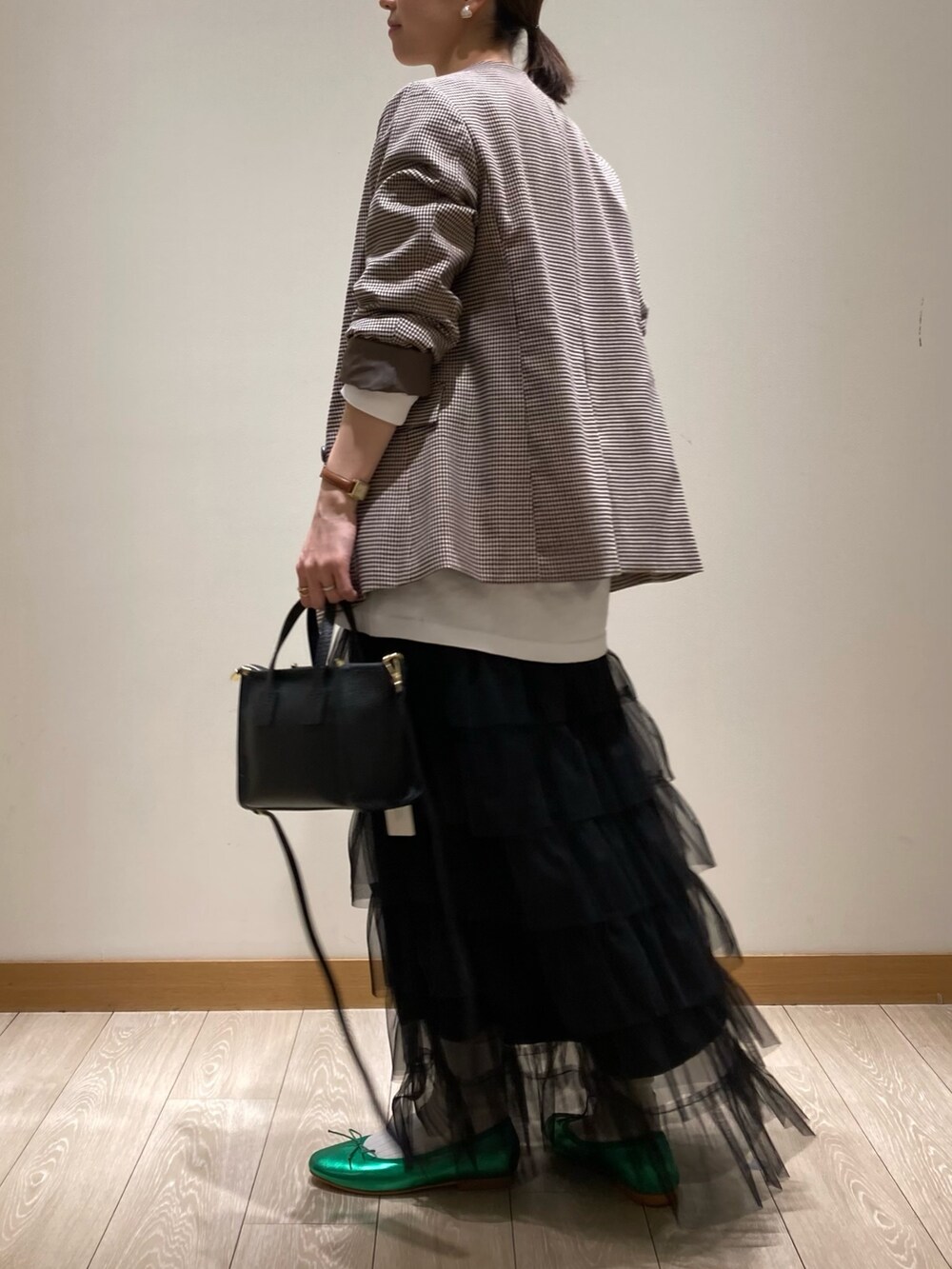 ブラック系のトートバッグ、ブラック系のスカート、グリーン系のバレエシューズを着用したレディースの春コーディネートの4枚目の写真