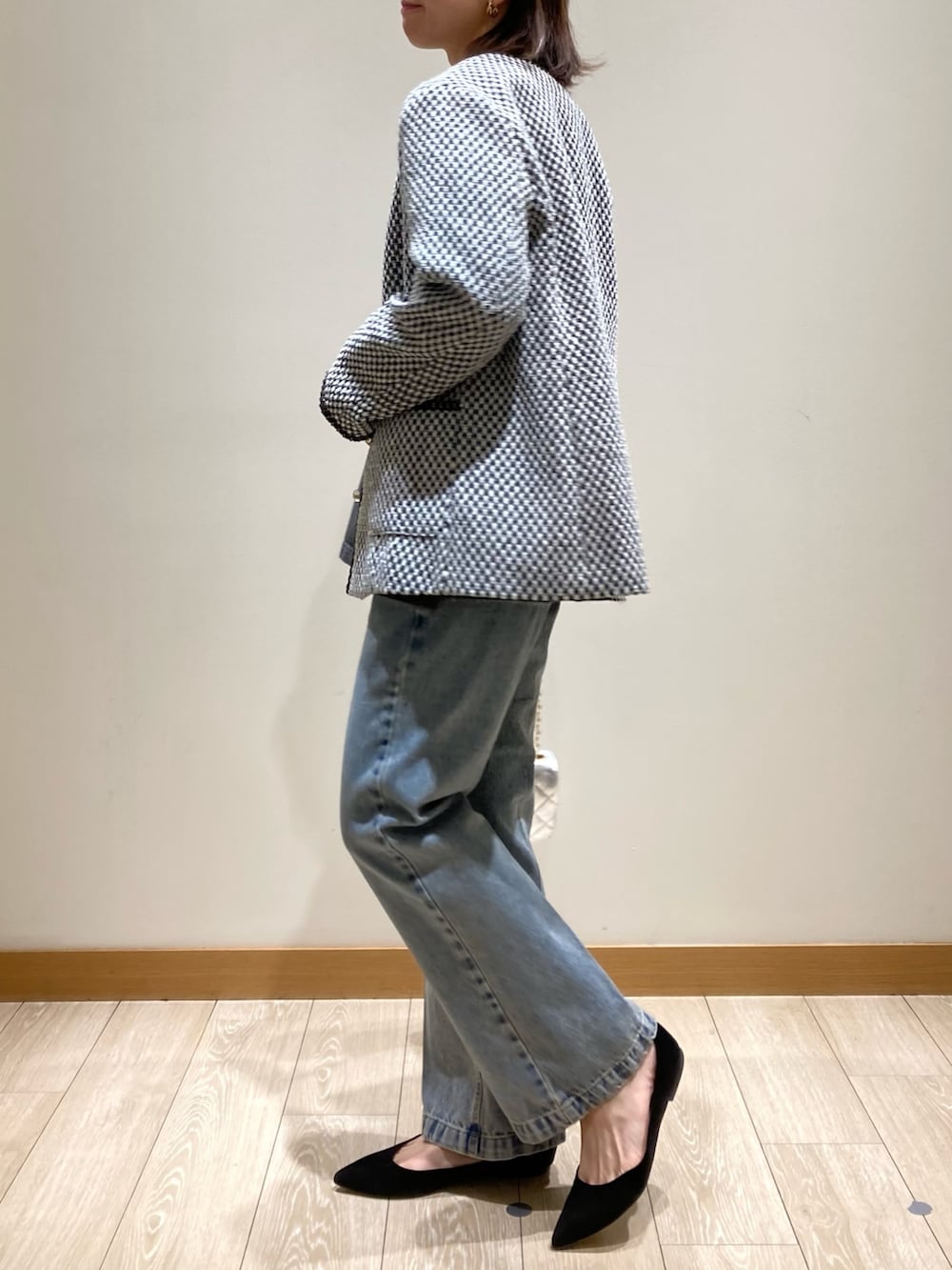 ブルー系のデニムパンツ、シルバー系のショルダーバッグ、ブラック系のノーカラージャケットを着用したレディースの冬コーディネートの4枚目の写真