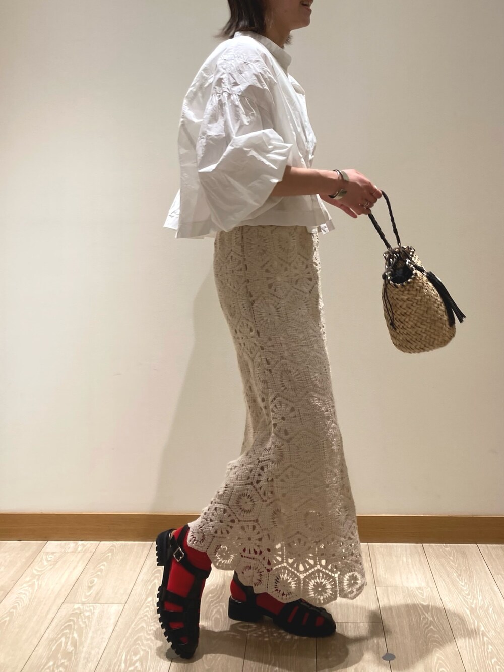 ホワイト系のスカート、ブラック系のサンダル、ブラック系のかごバッグを着用したレディースの春コーディネートの2枚目の写真