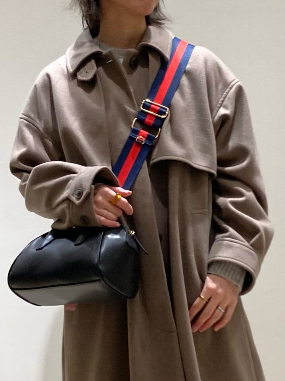 ブラウン系のステンカラーコート、ブラック系のボストンバッグ、ブラック系のブーツを着用したレディースの冬コーディネートの9枚目の写真