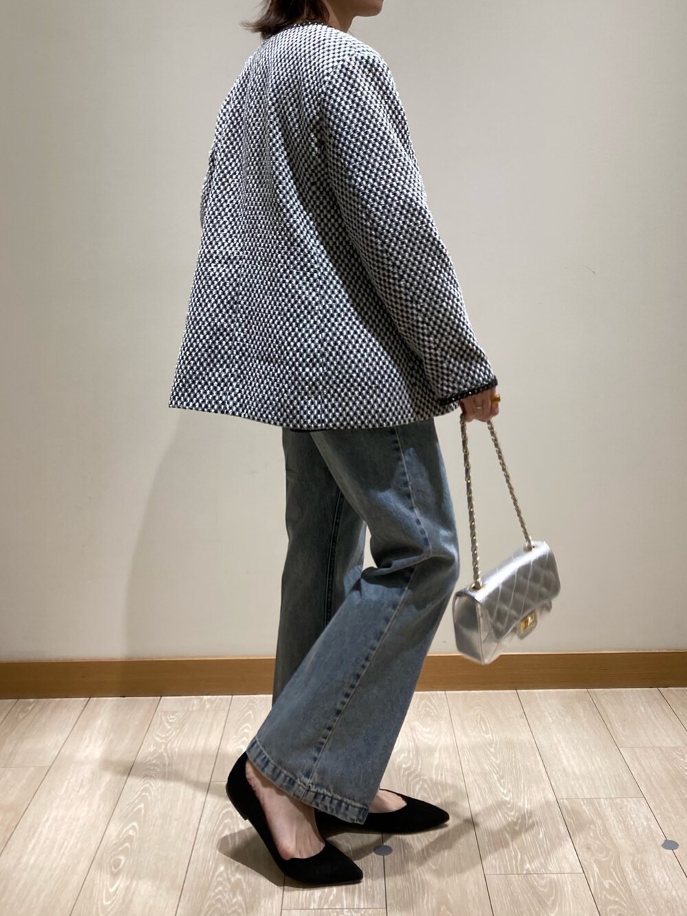 ブルー系のデニムパンツ、シルバー系のショルダーバッグ、ブラック系のノーカラージャケットを着用したレディースの冬コーディネートの3枚目の写真