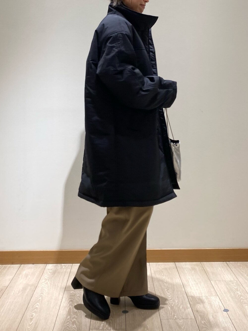 ベージュ系のスラックス、シルバー系のショルダーバッグ、ブラック系のブーツを着用したレディースの冬コーディネートの3枚目の写真