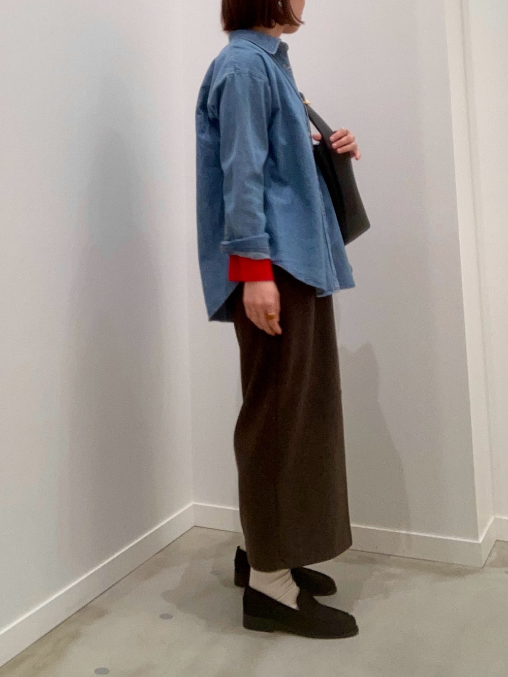 レッド系のニット/セーター、ブルー系のシャツ/ブラウス、ブラウン系のスカートを着用したレディースの冬コーディネートの4枚目の写真