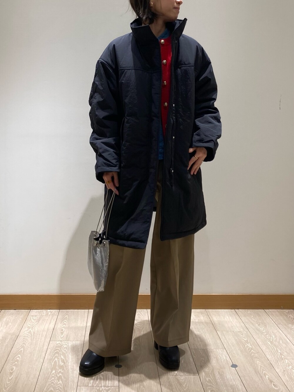 ベージュ系のスラックス、シルバー系のショルダーバッグ、ブラック系のブーツを着用したレディースの冬コーディネートの5枚目の写真