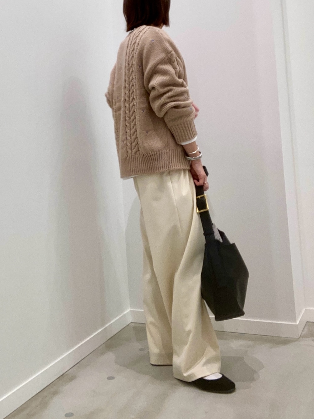 ベージュ系のニット/セーター、ホワイト系のTシャツ/カットソー、ブラック系のショルダーバッグを着用したレディースの秋コーディネートの3枚目の写真
