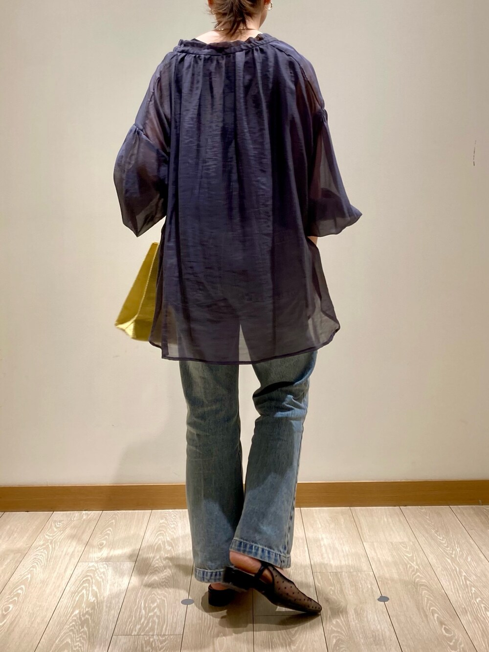 イエロー系のかごバッグ、ブルー系のデニムパンツ、ブラック系のパンプスを着用したレディースの春コーディネートの5枚目の写真