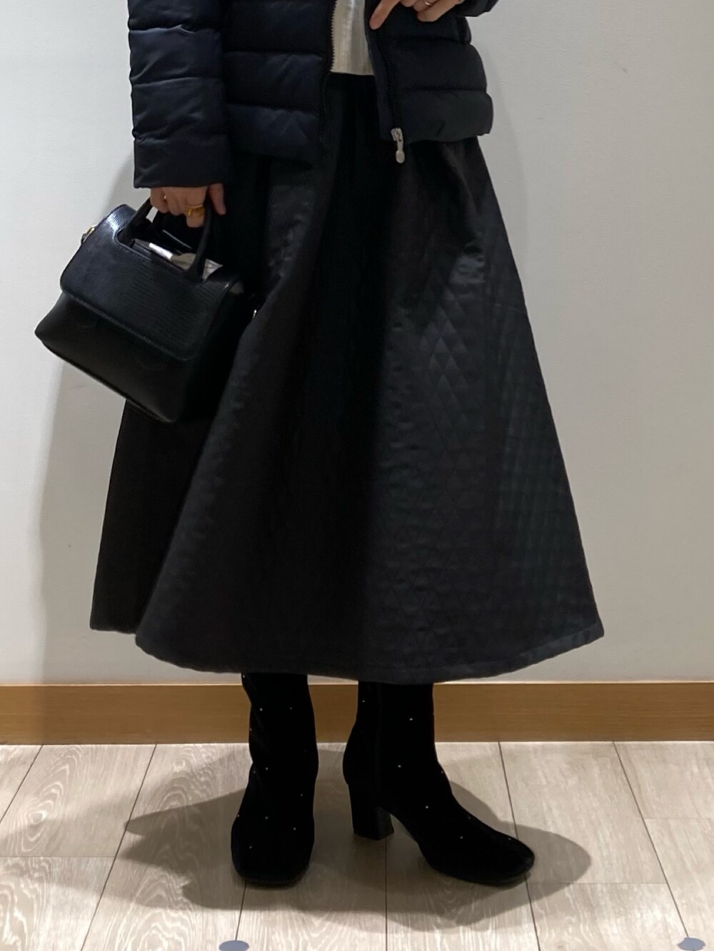 ブラック系のスカート、ホワイト系のニット/セーター、ブラック系のボストンバッグを着用したレディースの冬コーディネートの4枚目の写真