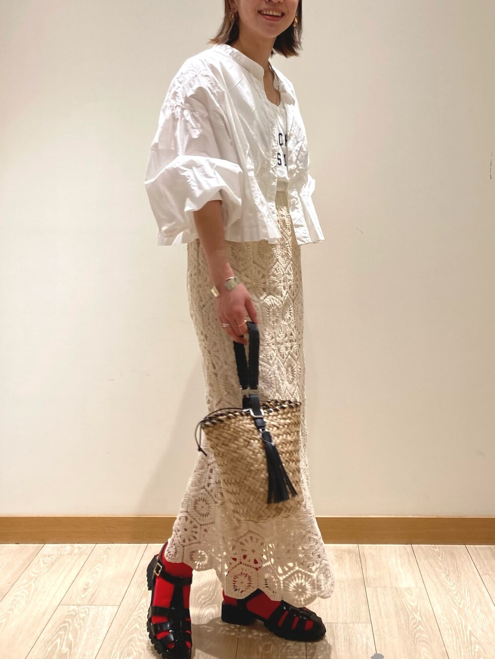 ホワイト系のスカート、ブラック系のサンダル、ブラック系のかごバッグを着用したレディースの春コーディネートの3枚目の写真