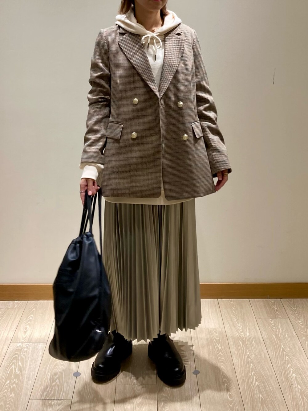 シルバー系のスカート、ベージュ系のテーラードジャケット、ホワイト系のパーカーを着用したレディースの秋コーディネートの7枚目の写真