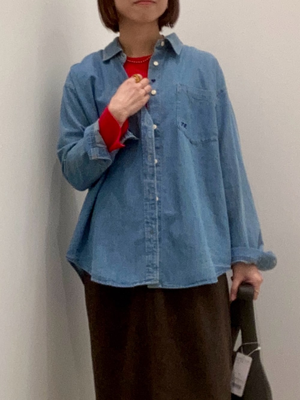 レッド系のニット/セーター、ブルー系のシャツ/ブラウス、ブラウン系のスカートを着用したレディースの冬コーディネートの8枚目の写真