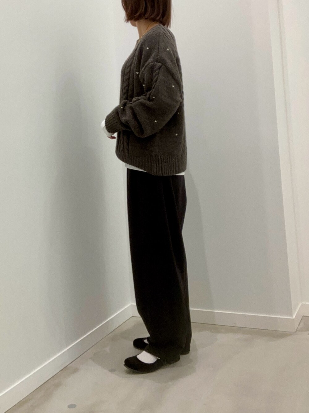 グレー系のニット/セーター、ホワイト系のTシャツ/カットソー、ブラック系のその他パンツを着用したレディースの秋コーディネートの6枚目の写真