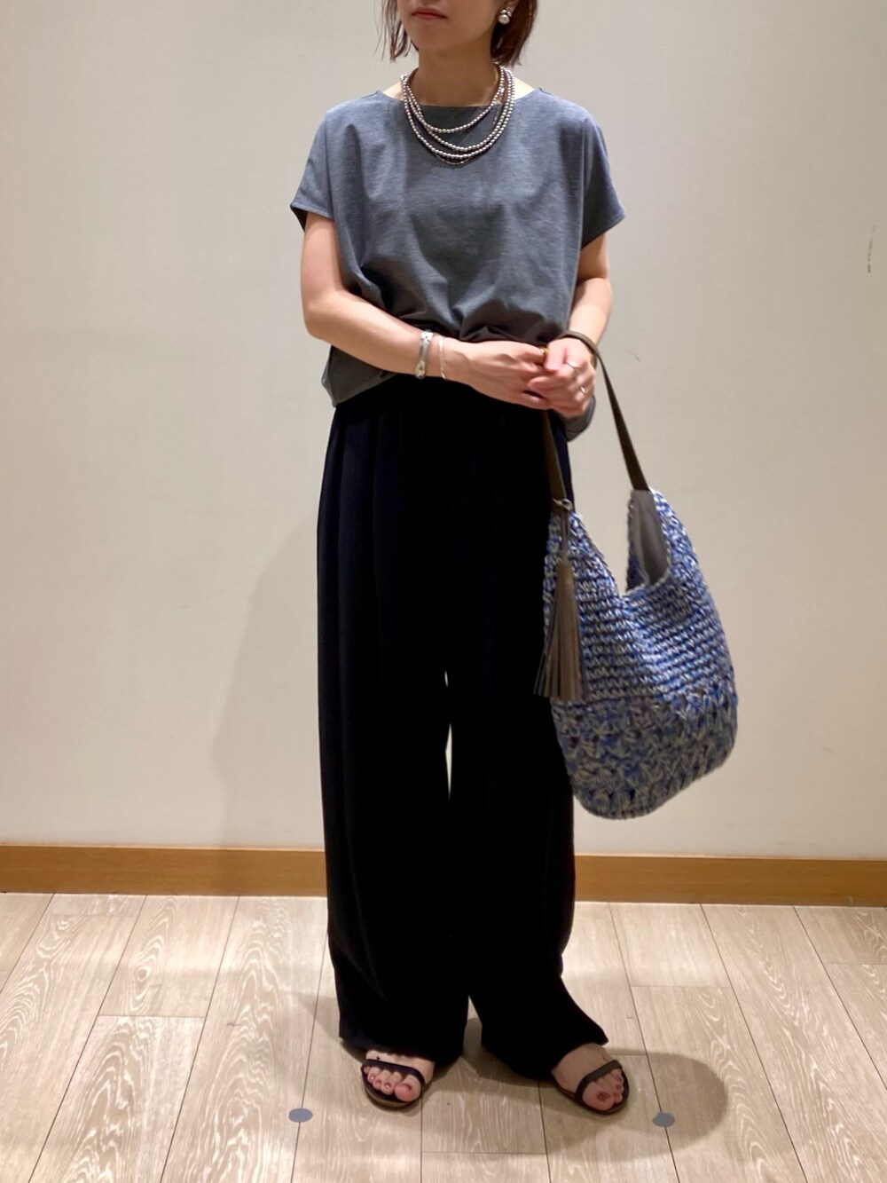 グレー系のTシャツ/カットソー、ブルー系のかごバッグ、ブラック系のその他パンツを着用したレディースの夏コーディネートの3枚目の写真