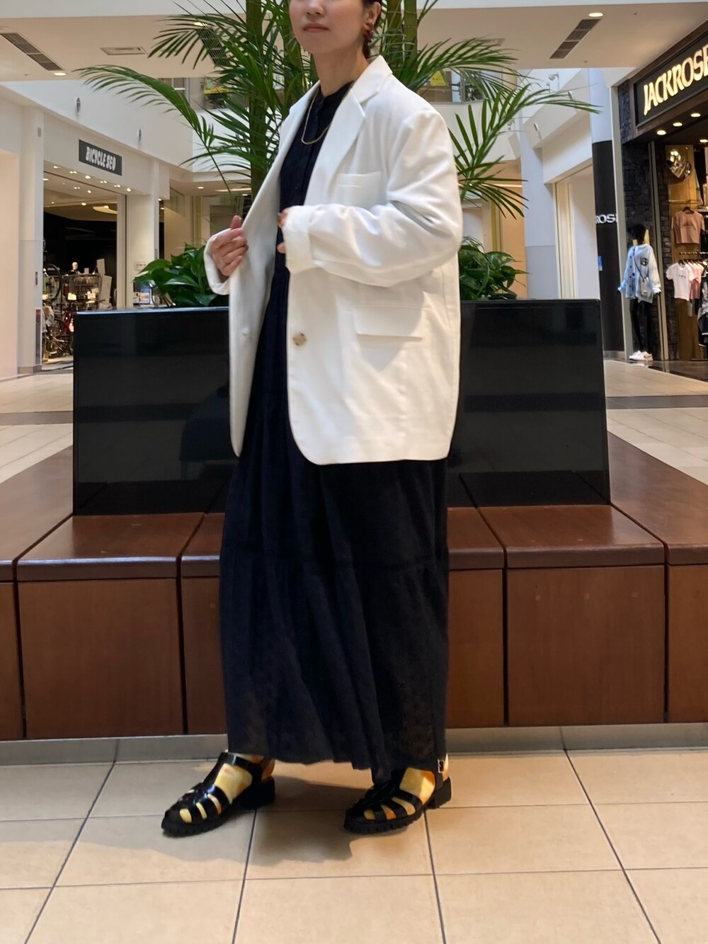 ホワイト系のテーラードジャケット、ブラック系のサンダル、ブラック系のワンピースを着用したレディースの春コーディネートの3枚目の写真