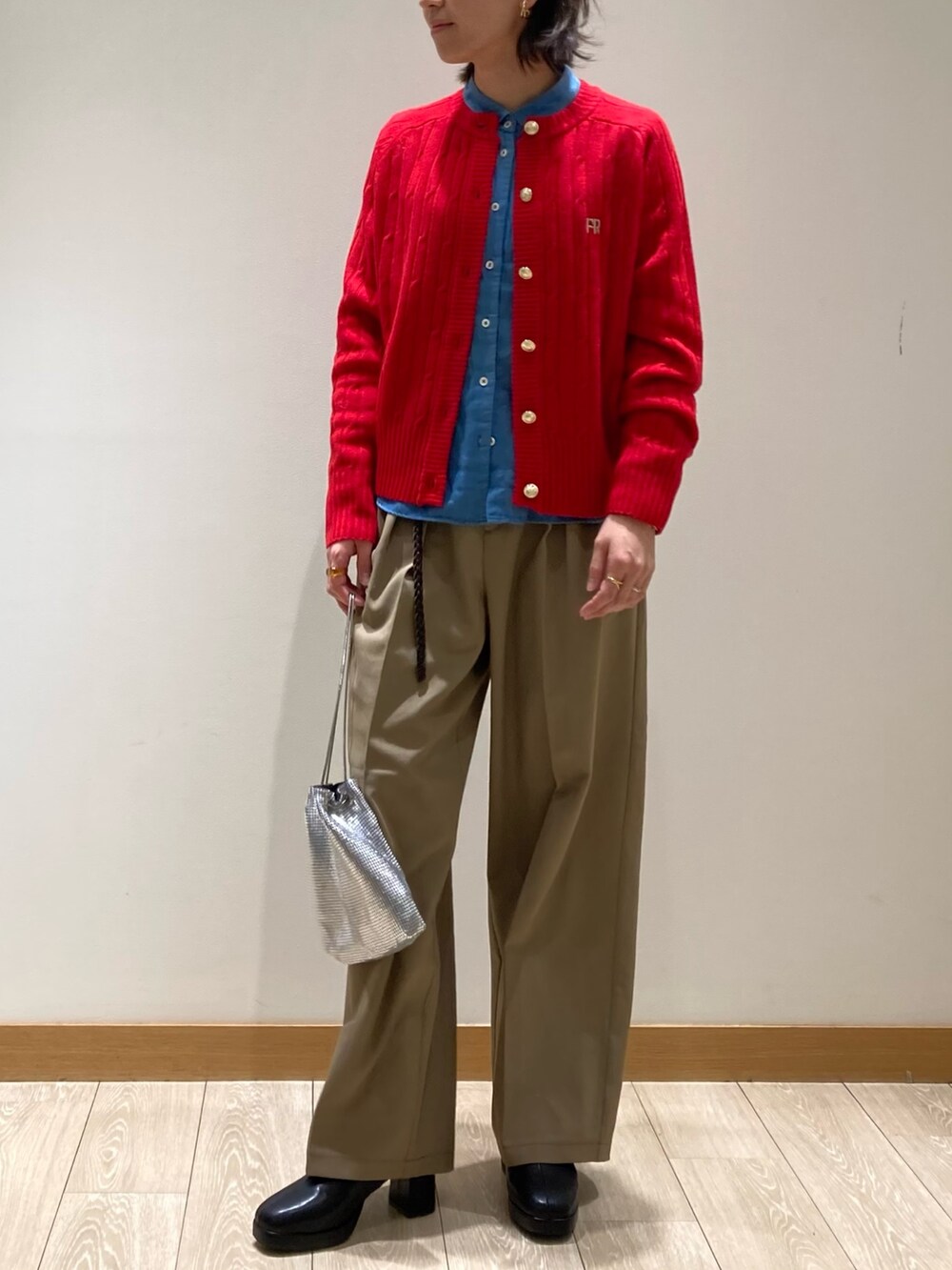 レッド系のカーディガン/ボレロ、ブラック系のブーツ、ベージュ系のスラックスを着用したレディースの冬コーディネートの5枚目の写真