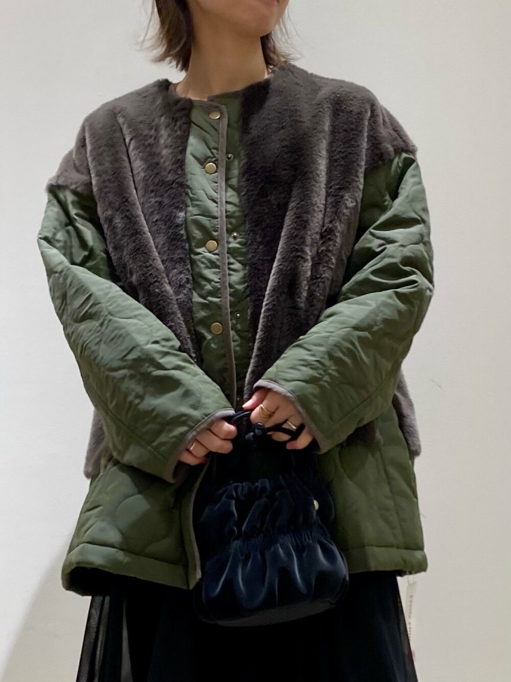 ブラック系のショルダーバッグ、ブラック系のワンピース、グリーン系のブルゾンを着用したレディースの冬コーディネートの5枚目の写真