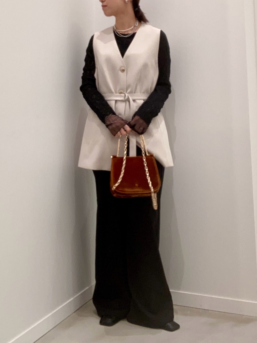 ベージュ系のベスト、ブラック系のTシャツ/カットソー、ブラウン系のショルダーバッグを着用したレディースの冬コーディネートの3枚目の写真