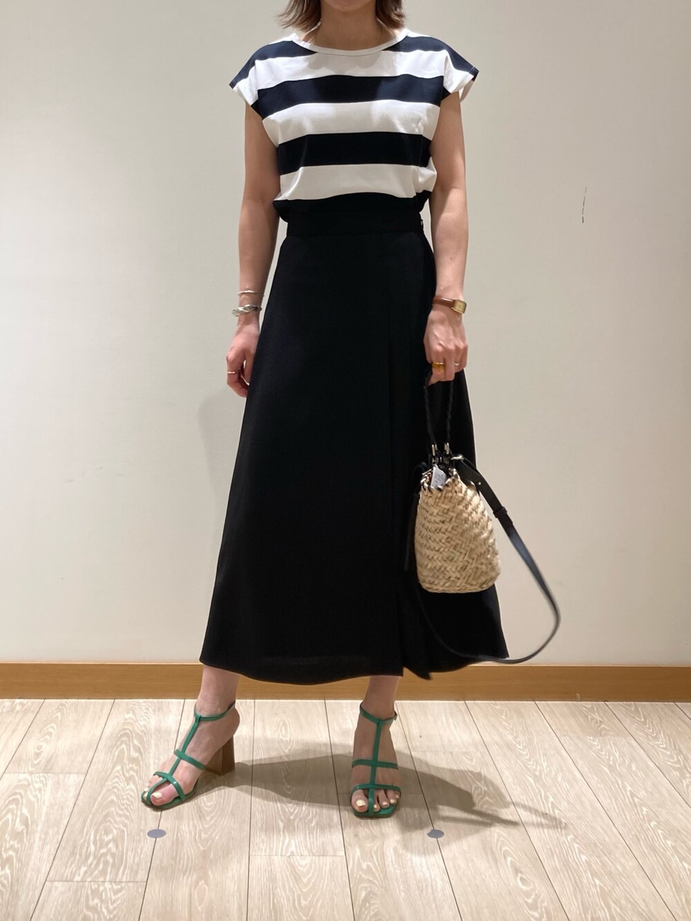 ブラック系のかごバッグ、ブラック系のスカート、ブラック系のTシャツ/カットソーを着用したレディースの春コーディネートの3枚目の写真