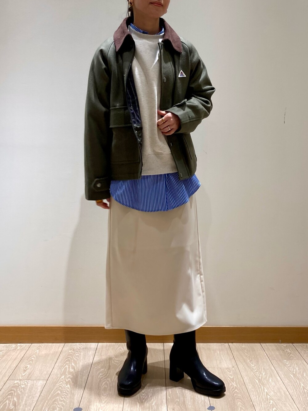 グリーン系のテーラードジャケット、グレー系のスウェット、ホワイト系のスカートを着用したレディースの冬コーディネートの2枚目の写真