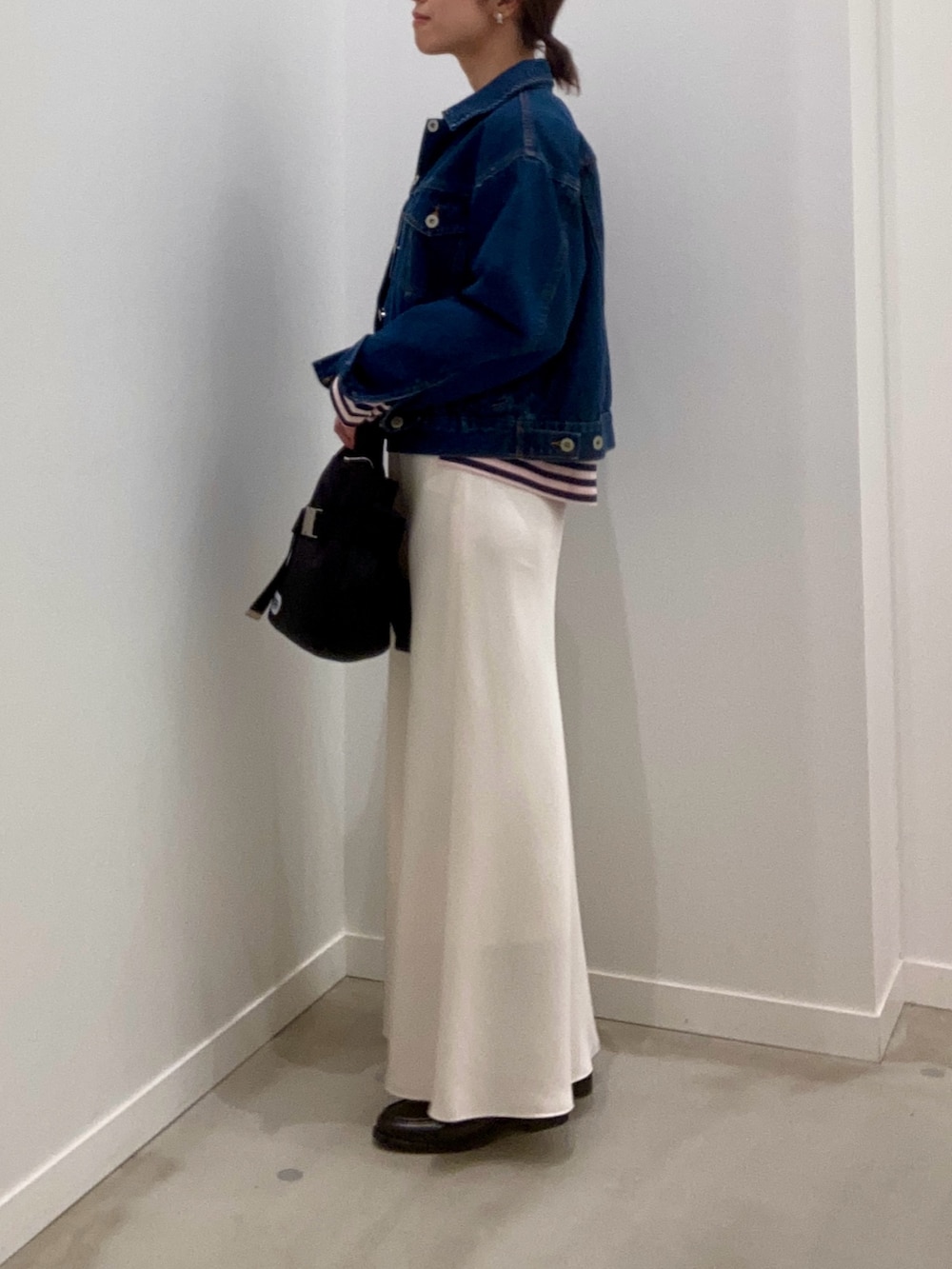 ブルー系のデニムジャケット、ホワイト系のスカート、ブラック系のその他シューズを着用したレディースの冬コーディネートの6枚目の写真