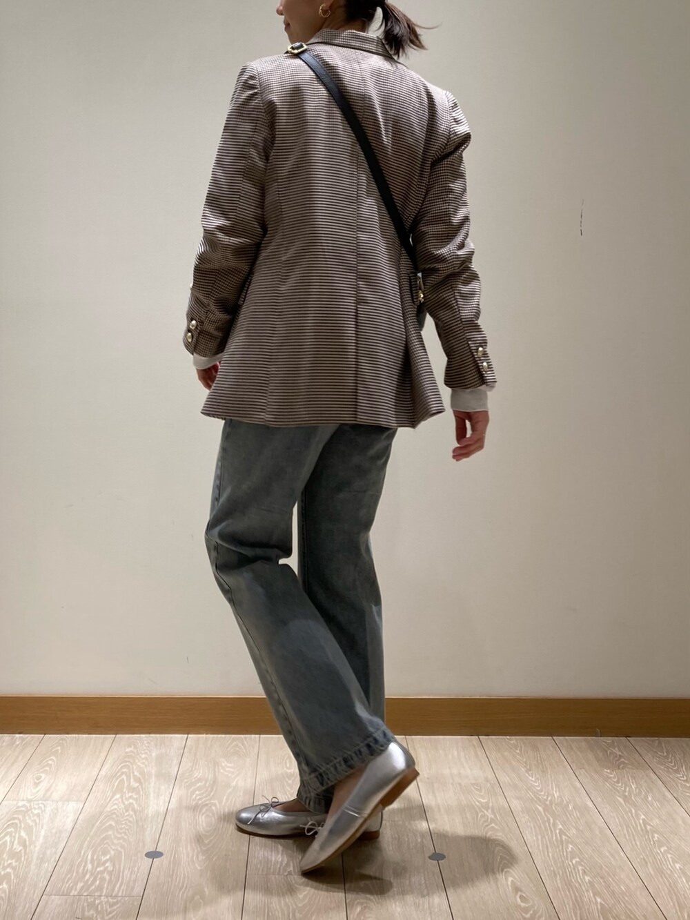 ブラック系のショルダーバッグ、ブルー系のデニムパンツ、シルバー系のバレエシューズを着用したレディースの冬コーディネートの3枚目の写真