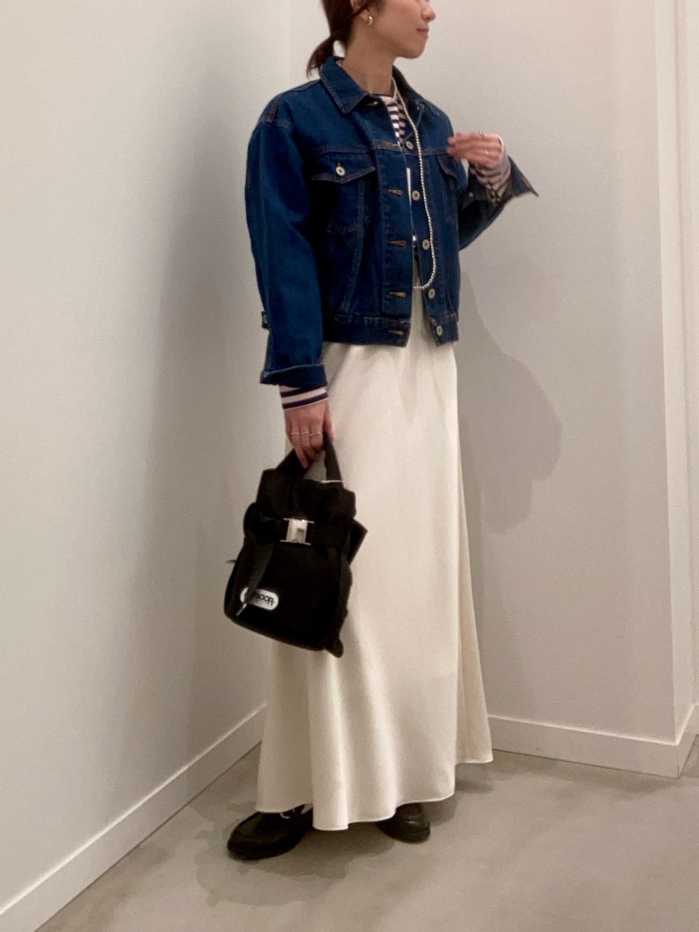 ブルー系のデニムジャケット、ホワイト系のスカート、ブラック系のその他シューズを着用したレディースの冬コーディネートの3枚目の写真