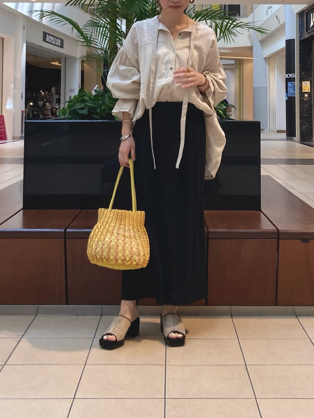 ブラック系のスカート、ベージュ系のシャツ/ブラウス、イエロー系のショルダーバッグを着用したレディースの春コーディネートの2枚目の写真