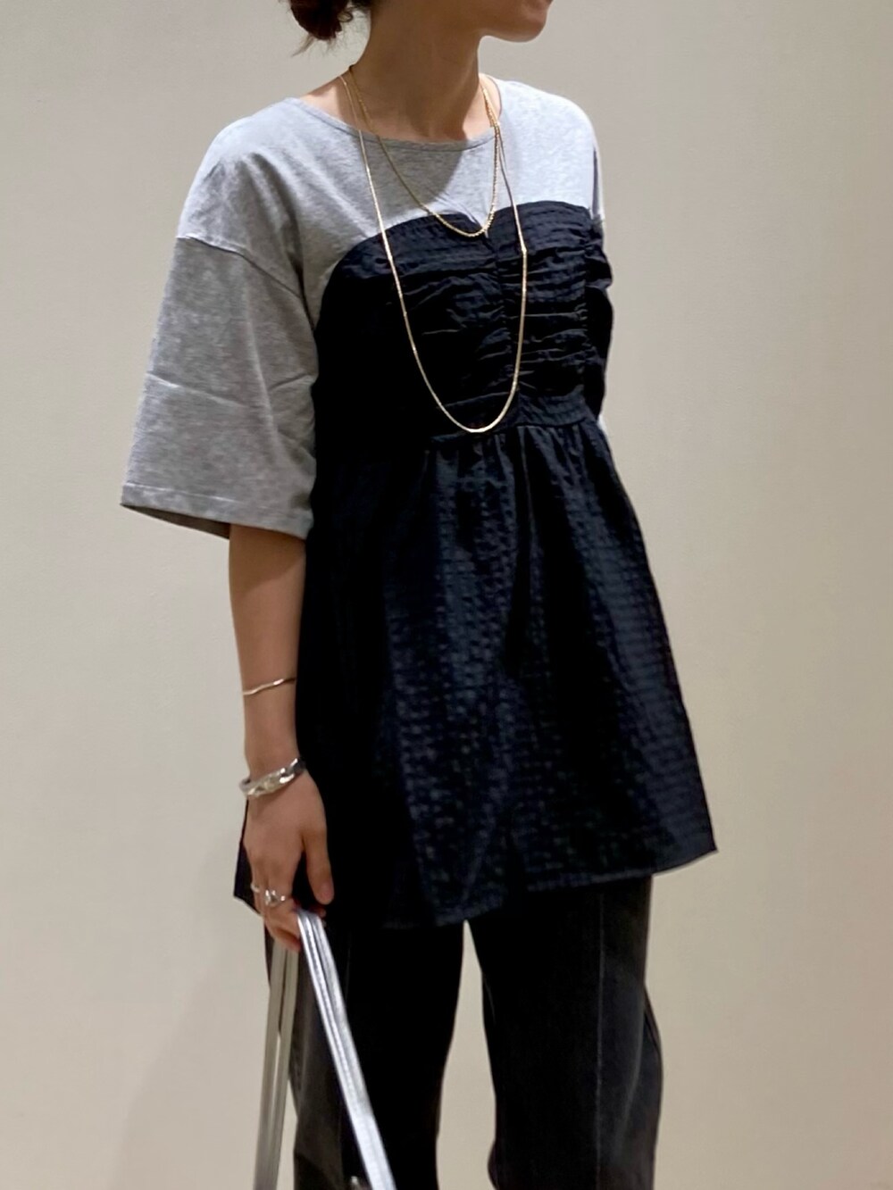 シルバー系のハンドバッグ、グレー系のTシャツ/カットソー、シルバー系のサンダルを着用したレディースの夏コーディネートの6枚目の写真